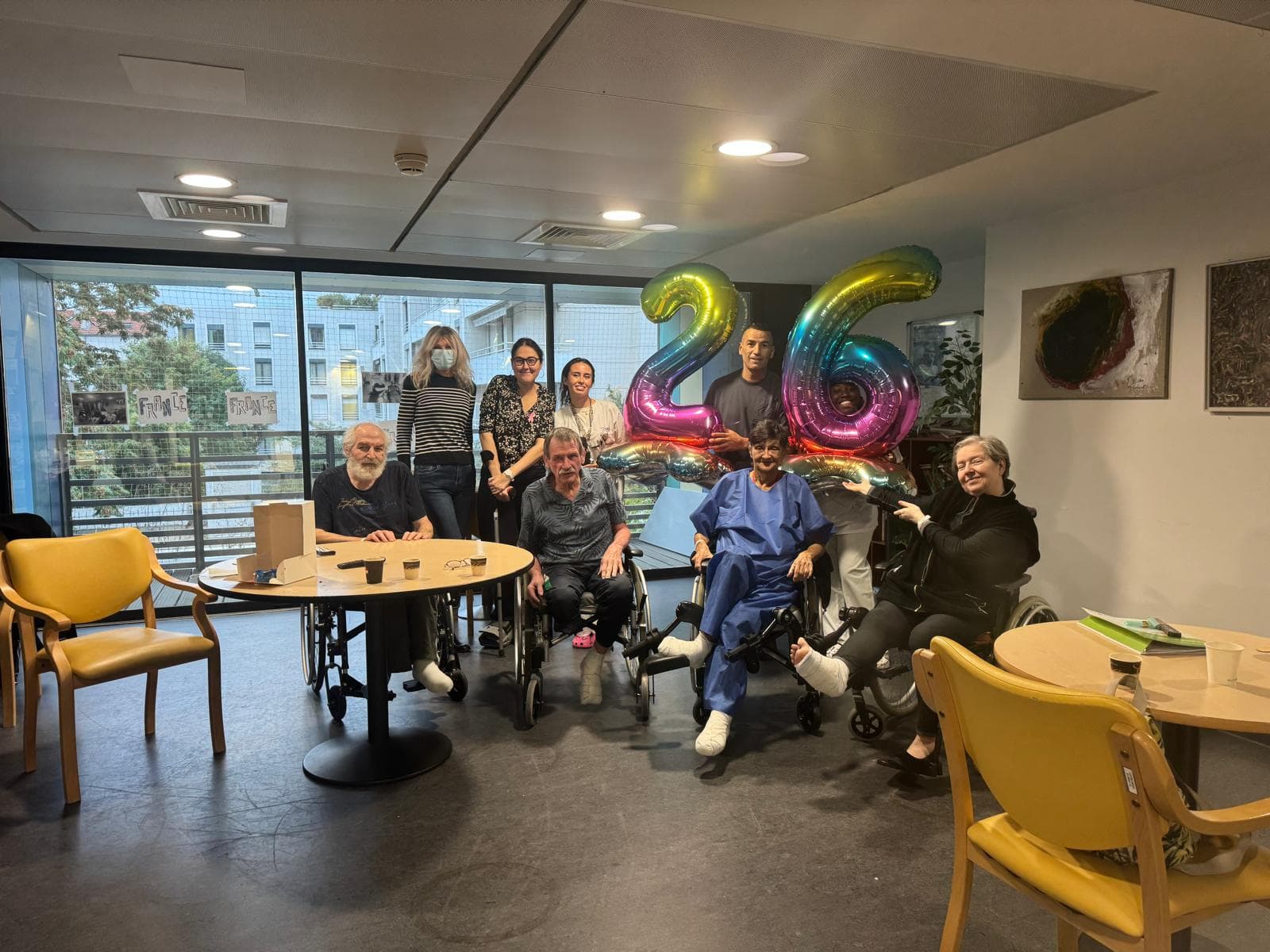Patients, soignants et visiteurs réunis autour de ballons lors d'un après-midi festif.